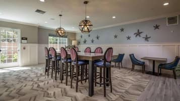 Uma sala de jantar com uma mesa comprida e cadeiras, um tapete estampado e decorações de estrelas nas paredes.