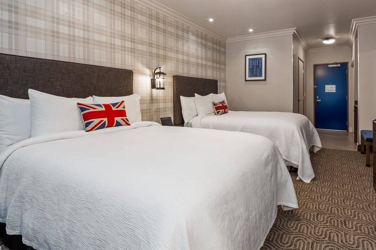 Une chambre d’hôtel avec deux lits, une télévision, un bureau et une moquette à motifs.