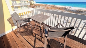 Une terrasse en bois avec une table et des chaises donnant sur une plage.