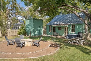 A rustic outdoor area with a fire pit, Adirondack chairs, and a picnic table.