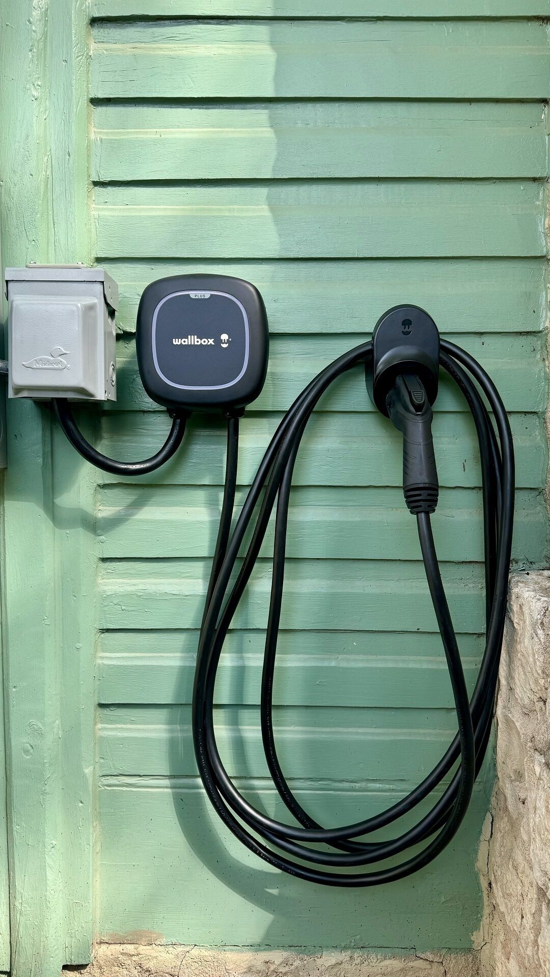 A green door with a wallbox and a power outlet.