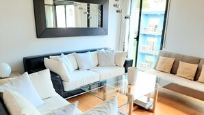 Una sala de estar moderna con un sofá negro, un sofá beige y una mesa de centro de vidrio.