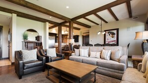 A spacious living room with a large sofa, two armchairs, and a wooden coffee table. The room features exposed wooden beams on the ceiling and a large mirror above the sofa. - Silver Star 1303 | Park City Condo with Pool Access, Hot Tub and Mountain Views (Park City)