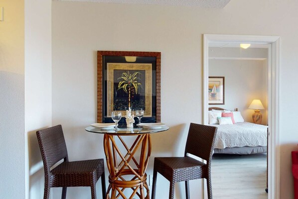 A room with a bed, a table with chairs, and a painting on the wall.
