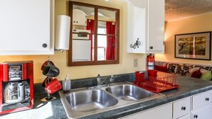 A kitchen with a double sink, a coffee maker, and a red dish rack. - Cyclismo - Suite 2 | Close to Main St. | Wonderful Porch (Fredricksburg)