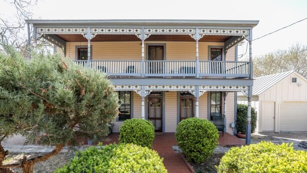 A two-story house with a balcony, a front porch, and a garage. - Cyclismo - Suite 2 | Close to Main St. | Wonderful Porch (Fredricksburg)