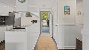 A kitchen with white cabinetry, a stainless steel refrigerator, and a clock on the wall. - Unit 27, The Sail Away, 2 Bedroom Beach Condo (Panama City Beach)