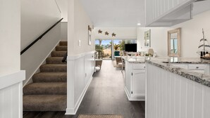 A modern kitchen with white cabinetry, a granite countertop, and a view to the outdoors. - Unit 27, The Sail Away, 2 Bedroom Beach Condo (Panama City Beach)