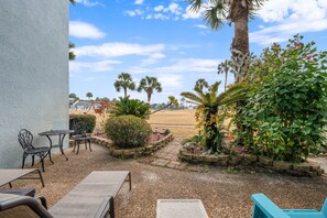 An outdoor patio area with seating, palm trees, and a view of the beach. - Unit 27, The Sail Away, 2 Bedroom Beach Condo (Panama City Beach)