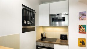 Una cucina moderna con mobili bianchi, elettrodomestici in acciaio inossidabile e un piano di lavoro in legno.
