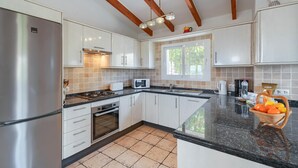Uma cozinha moderna com armários brancos, uma geladeira de aço inoxidável, um micro-ondas e um fogão.