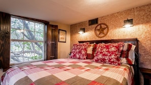 Un dormitorio con una cama grande, una ventana con vistas a árboles y una decoración con estrellas en la pared.
