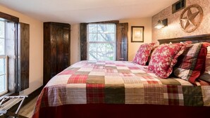 A bedroom with a large bed, a window, a wooden door, and a wall-mounted star decoration.