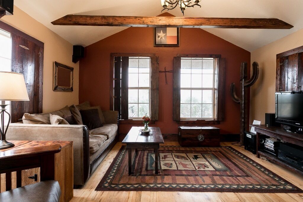 A cozy living room with a wooden ceiling, a sofa, a coffee table, a television, and a large window.