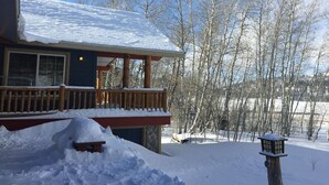Una casa con techo nevado y terraza de madera.