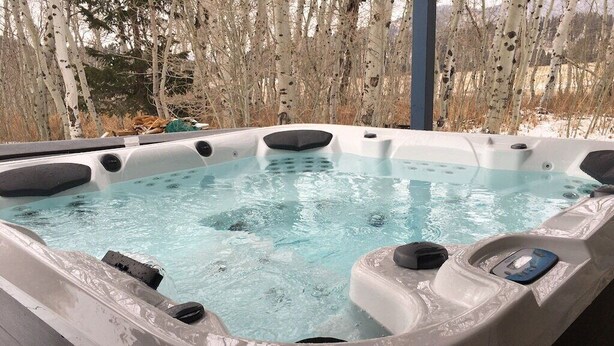 Un jacuzzi con vistas despejadas a los árboles circundantes y una terraza de madera.