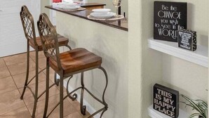 Una cucina con angolo bar, luci a sospensione ed elementi decorativi a mensola con scritte motivazionali.