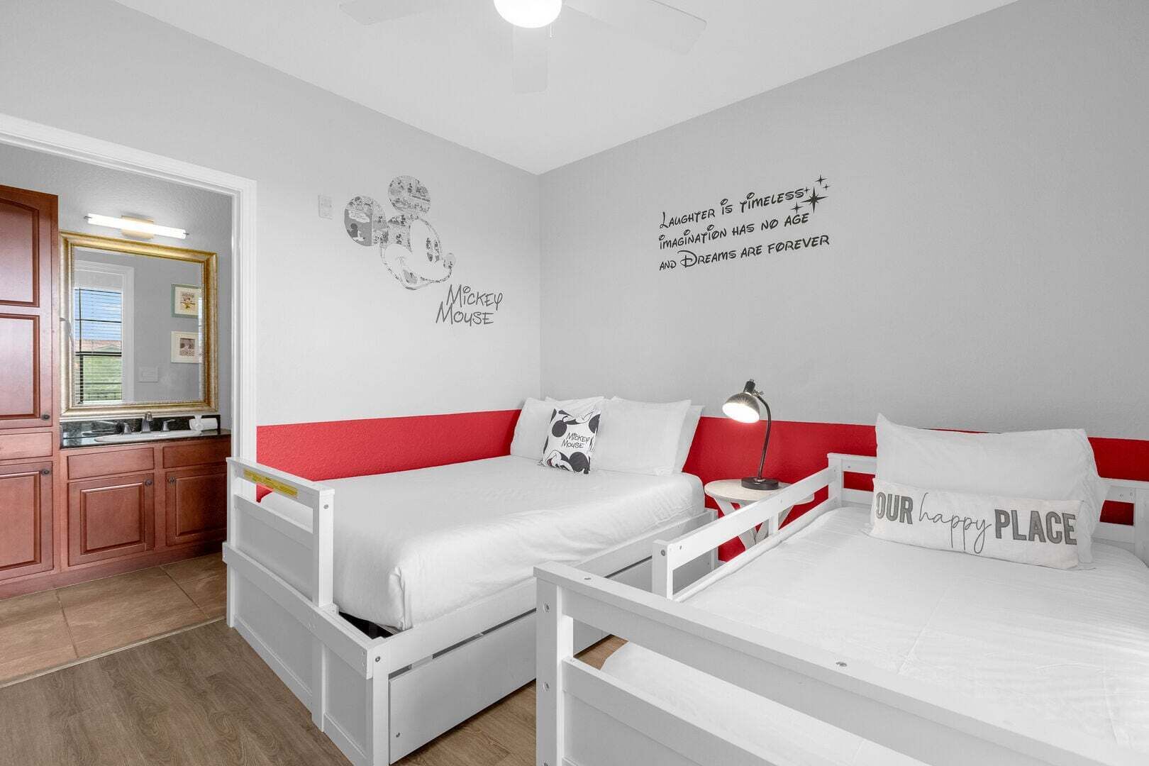 A bedroom with two beds, a red and white color scheme, Mickey Mouse wall art, and motivational quotes.