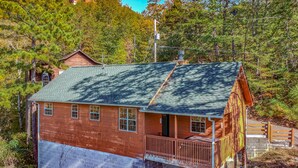 A wooden cabin with a green roof, surrounded by trees. - Ladybug Resort Romantic Cabin with Mountain Views (Sevierville)