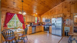 A wooden cabin kitchen with a dining table, chairs, a refrigerator, a microwave, and a dishwasher. - Ladybug Resort Romantic Cabin with Mountain Views (Sevierville)