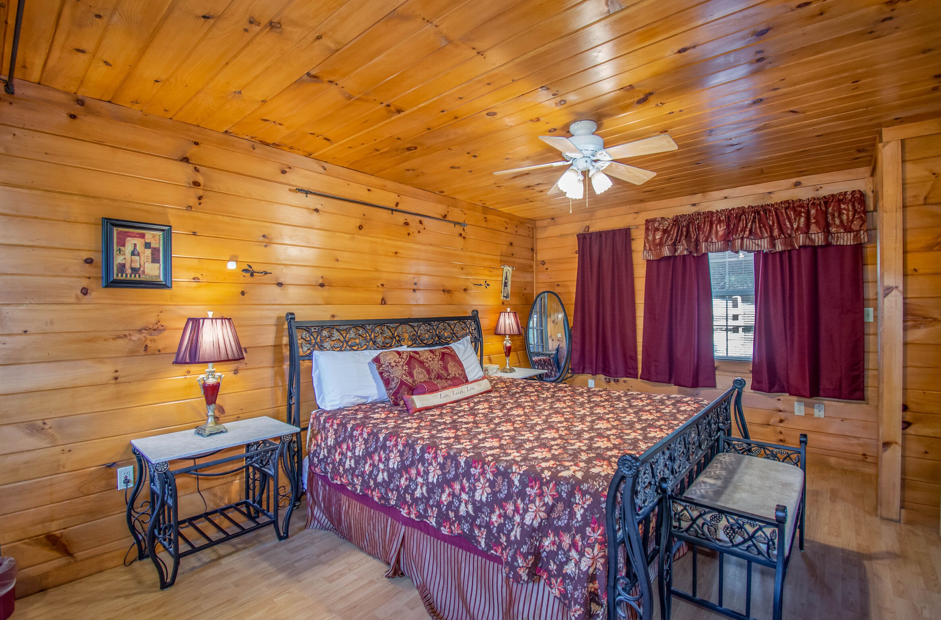 A wooden cabin bedroom with a bed, a nightstand, a chair, and a ceiling fan.