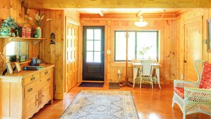 A wooden interior with a dining area, a black door, and a window.