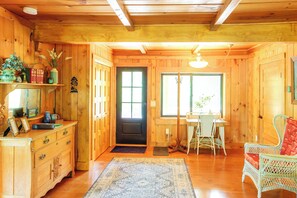 A wooden interior with a dining area, a black door, and a window. - Serene Wilderness Acres Retreat on Bear Lake (McGrath)