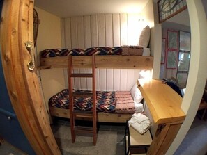 Cozy retreat with a bunk bed arrangement, wooden ladder, and compact desk area.