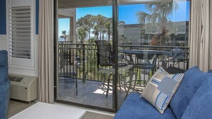 A room with a sliding glass door leading to an outdoor patio with a table and chairs. - Amazing Ocean Views! Minutes to Coligny Plaza (Hilton Head Island)