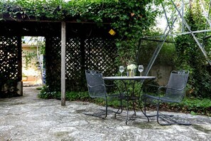 An outdoor patio with a table and two chairs, surrounded by greenery and a lattice fence. - Austin Street Retreat - Eli's Suite | 1 Block to Main (Fredricksburg)