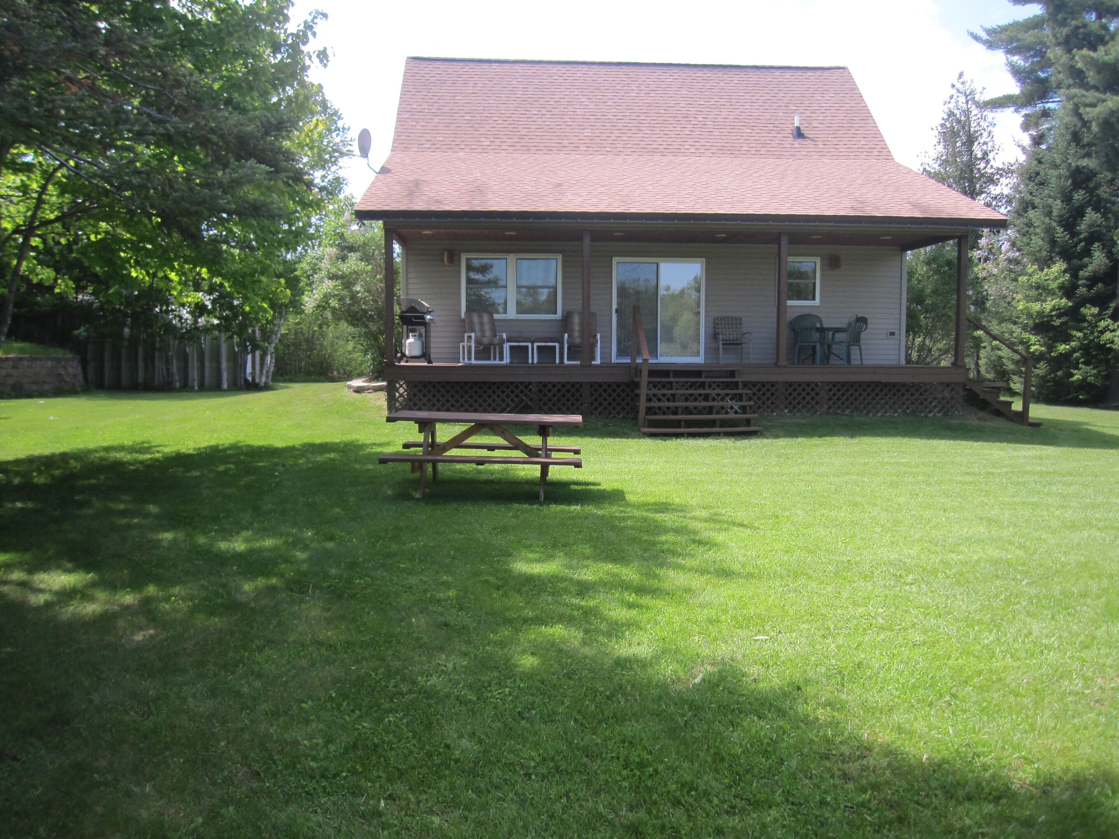 A house with a covered porch, a picnic table, and a lawn.