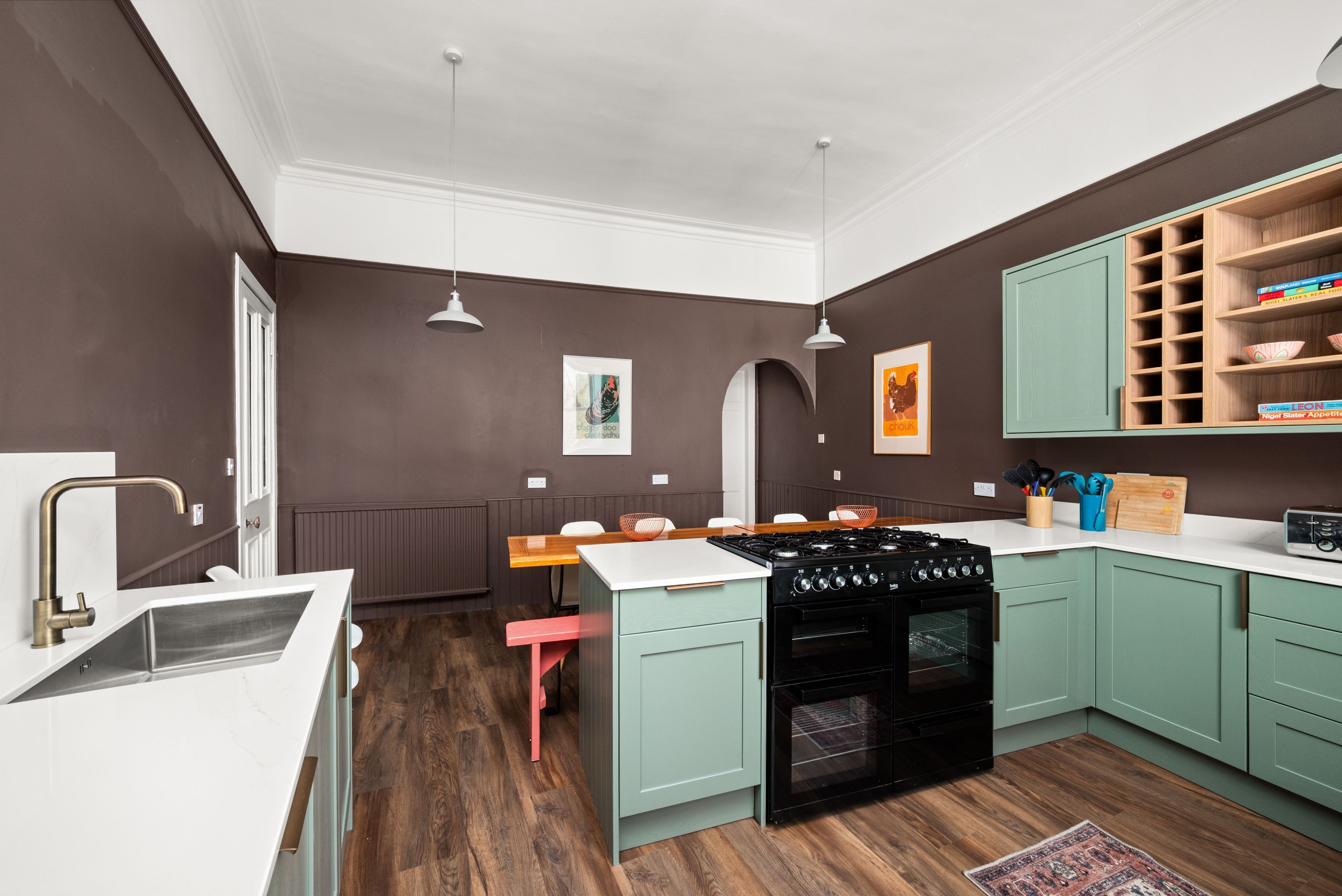 Cocina moderna con estufa a gas, un lavamanos y armarios verde claro.