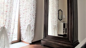 A room with a large mirror, floral curtains, and a wooden cabinet. - Umberto I Holiday House (Napoli)