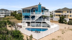 Una casa de varios pisos con piscina, balcones y vista al mar.