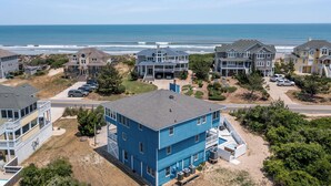 Zona residencial costera con varias casas de dos pisos, vista al mar y un estacionamiento.