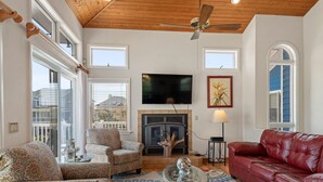 Una sala de estar con chimenea, televisor y sofá de cuero rojo.