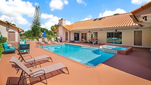 Ein Schwimmbecken mit Liegestühlen und einer überdachten Terrasse.
