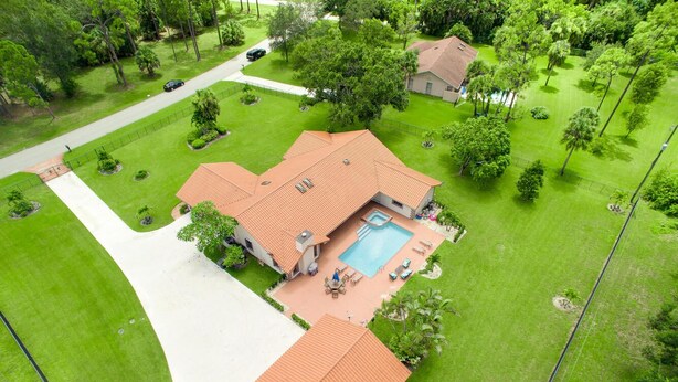 Ein zweistöckiges Haus mit Swimmingpool, umgeben von gepflegten Rasenflächen und Bäumen.