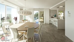 Un comedor moderno con una mesa redonda y sillas, una lámpara colgante y vistas al exterior.