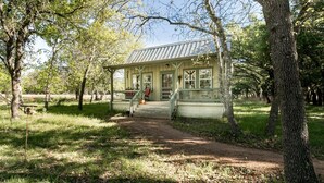 Un chalet rustique doté d’un porche, entouré d’arbres et bordé d’un sentier de terre.