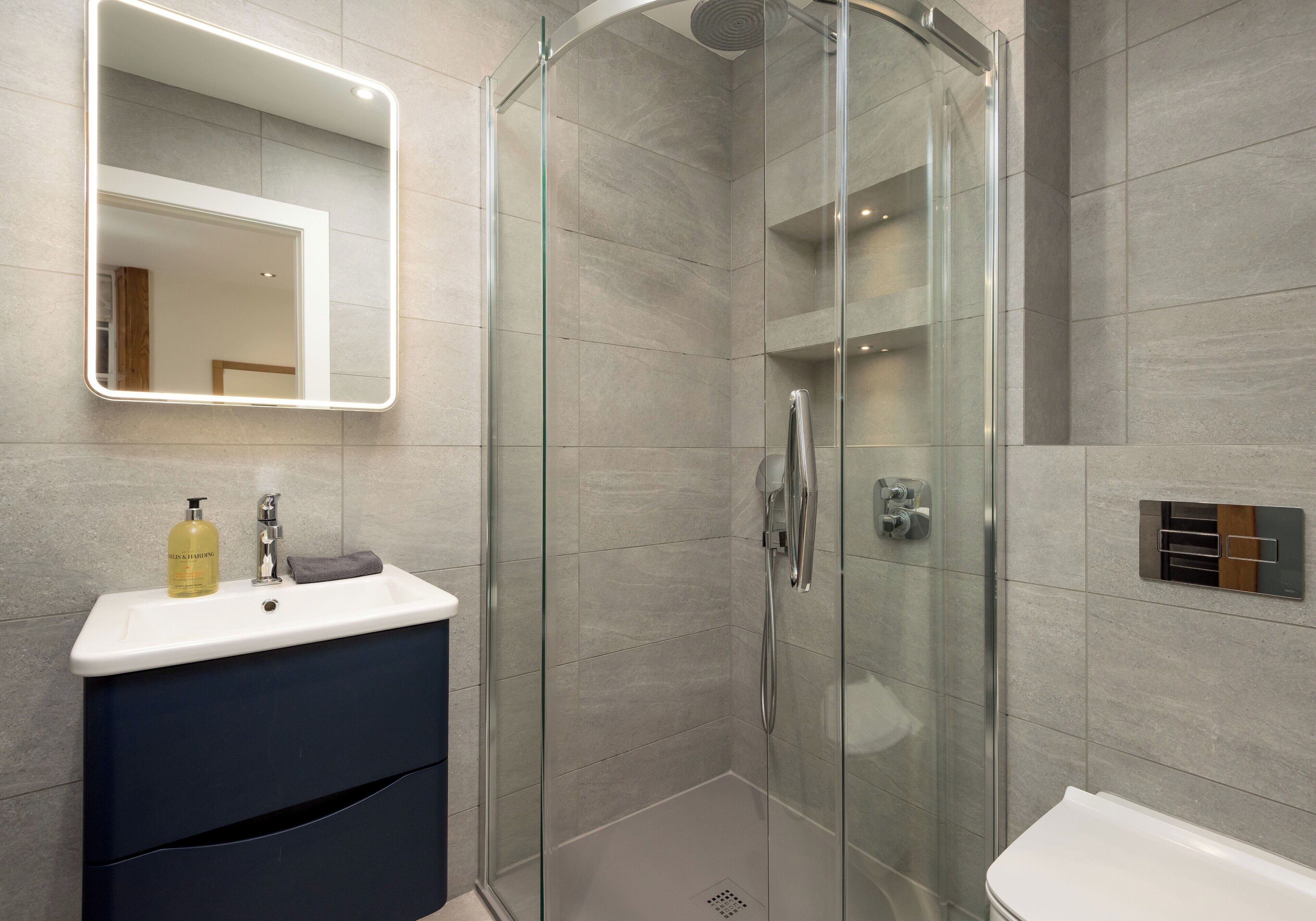 A modern bathroom with a glass-enclosed shower, a vanity with a mirror, and a toilet.