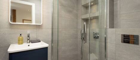 A modern bathroom with a glass-enclosed shower, a vanity with a mirror, and a toilet.