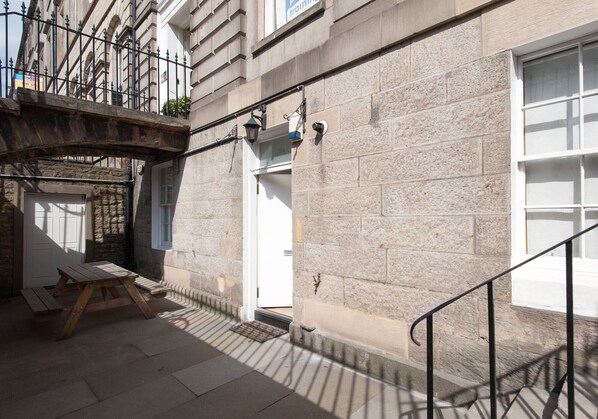 A stone building with a wooden bench and a metal railing.