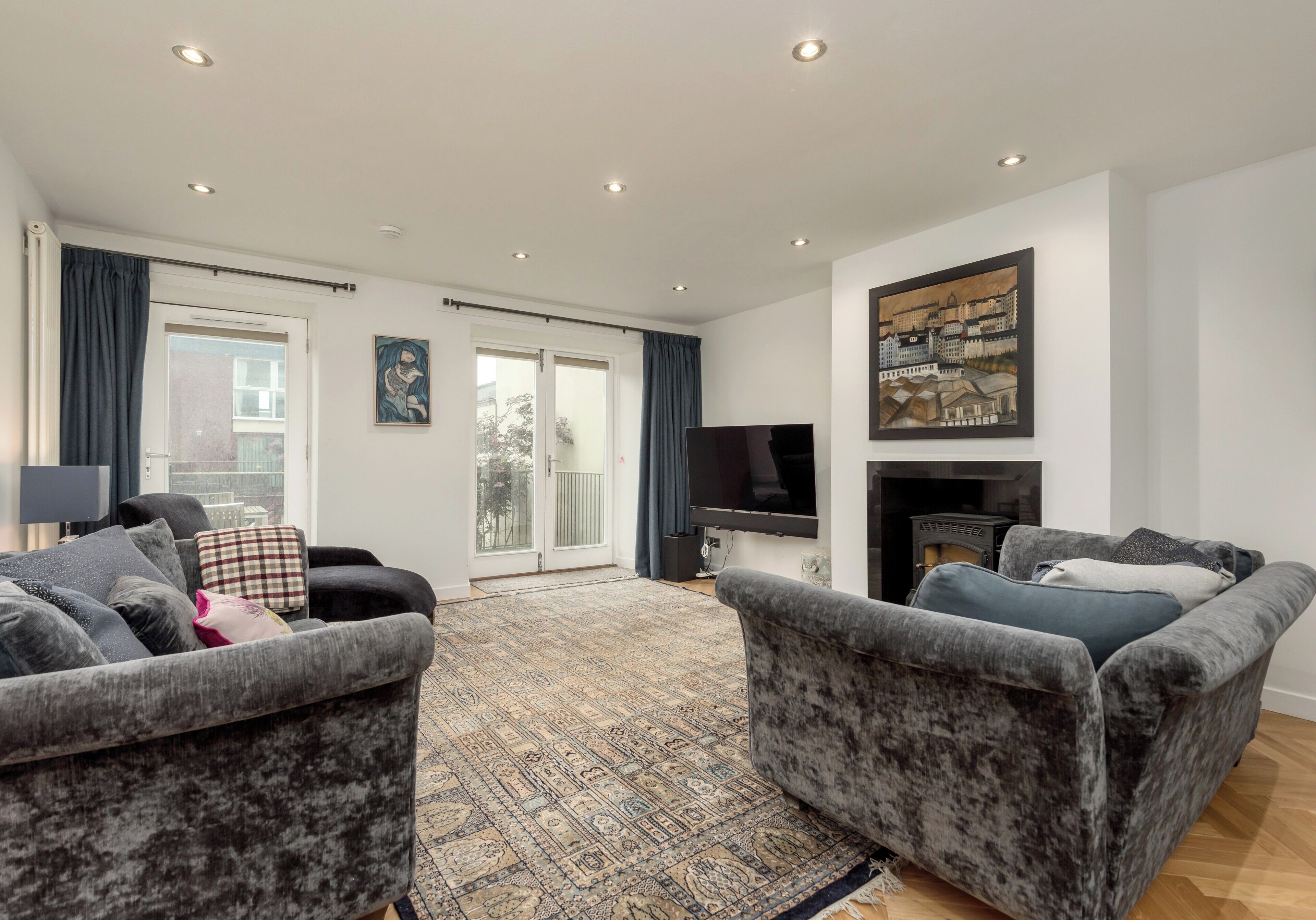 A living room with two grey sofas, a patterned rug, a flat-screen TV, and a fireplace.