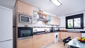 Une cuisine moderne dotée d’appareils électroménagers intégrés, un coin repas avec une table et des chaises, et une fenêtre offrant une vue agréable.