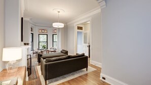 Un salon spacieux avec un grand canapé, un coin repas avec des chaises et une table sur laquelle se trouve une lampe.