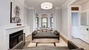 Un salon spacieux avec une cheminée, un grand canapé, une table basse et un coin repas avec des chaises.