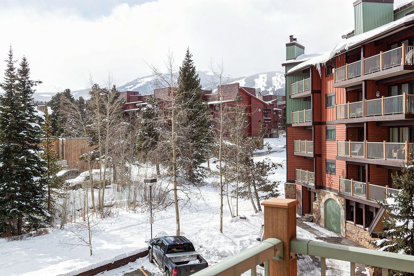 Un paysage enneigé avec un immeuble à plusieurs étages doté de balcons, et une piste de ski en arrière-plan.