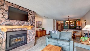 A living room with a stone fireplace, a flat-screen TV, a sofa, and a coffee table.