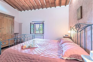 Relax in this charming bedroom with a comfortable bed, wooden wardrobe, and a beautiful floral arrangement.